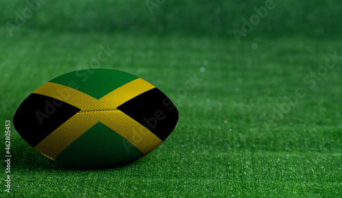 American football ball  with Jamaica flag on green grass background  close up