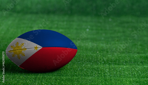 American football ball  with Philippines flag on green grass background  close up