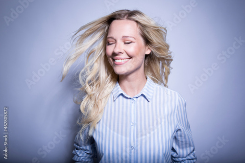 Portrait of happy blond woman tossing her hair photo