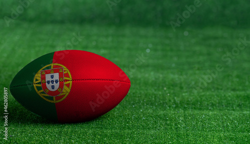 American football ball with Portugal flag on green grass background, close up