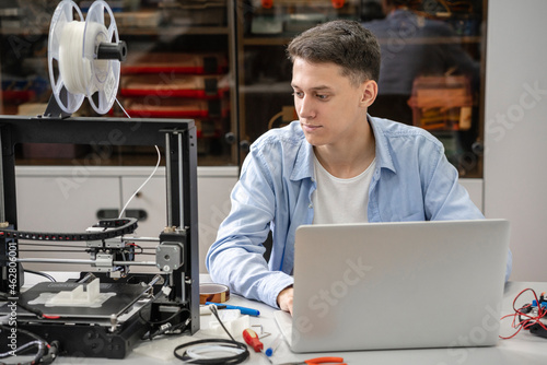 Student setting up 3D printer, using laptop photo