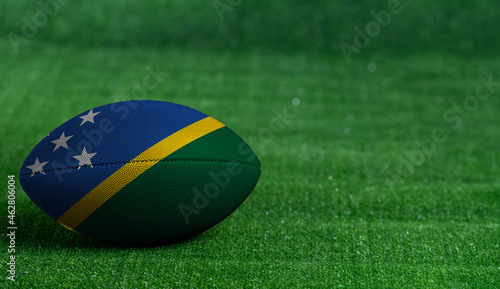 American football ball  with Solomon Islands flag on green grass background  close up