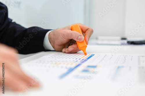 Close-up of businessman using highlighter on a report at desk in office photo