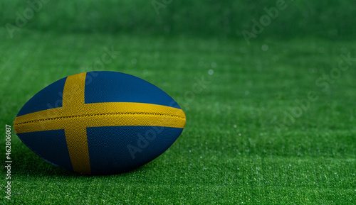 American football ball  with Sweden flag on green grass background  close up