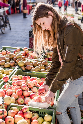 Girl with cloth bag choosing apples on weekly market