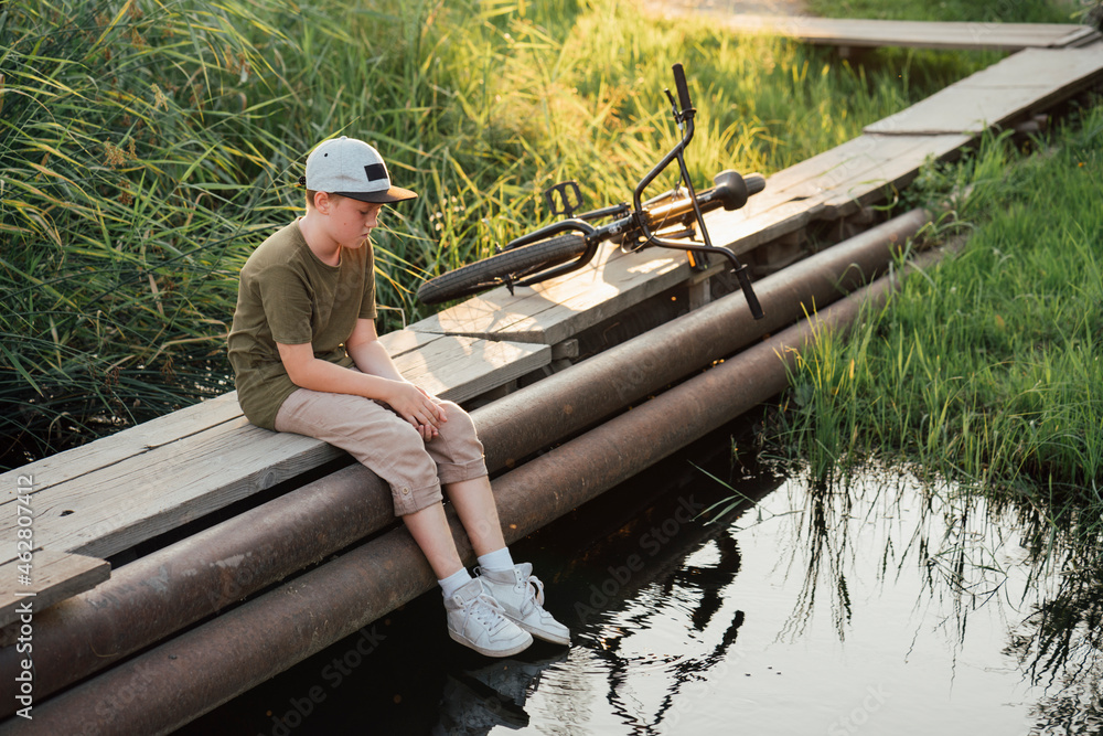 Serious boy woith bmx bike sitting on boardwalk Stock Photo Adobe Stock