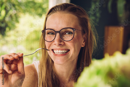 Portrait of happy young woman with glasses holding a fork photo
