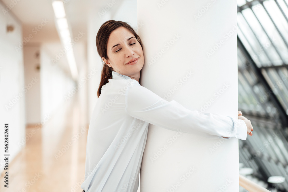 Female entrepreneur embracing architectural column at office corridor Female entrepreneur embracing architectural column at office corridor