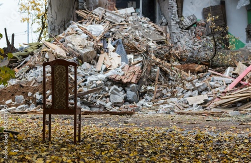 a chair stands on the street against the background of a destroyed house