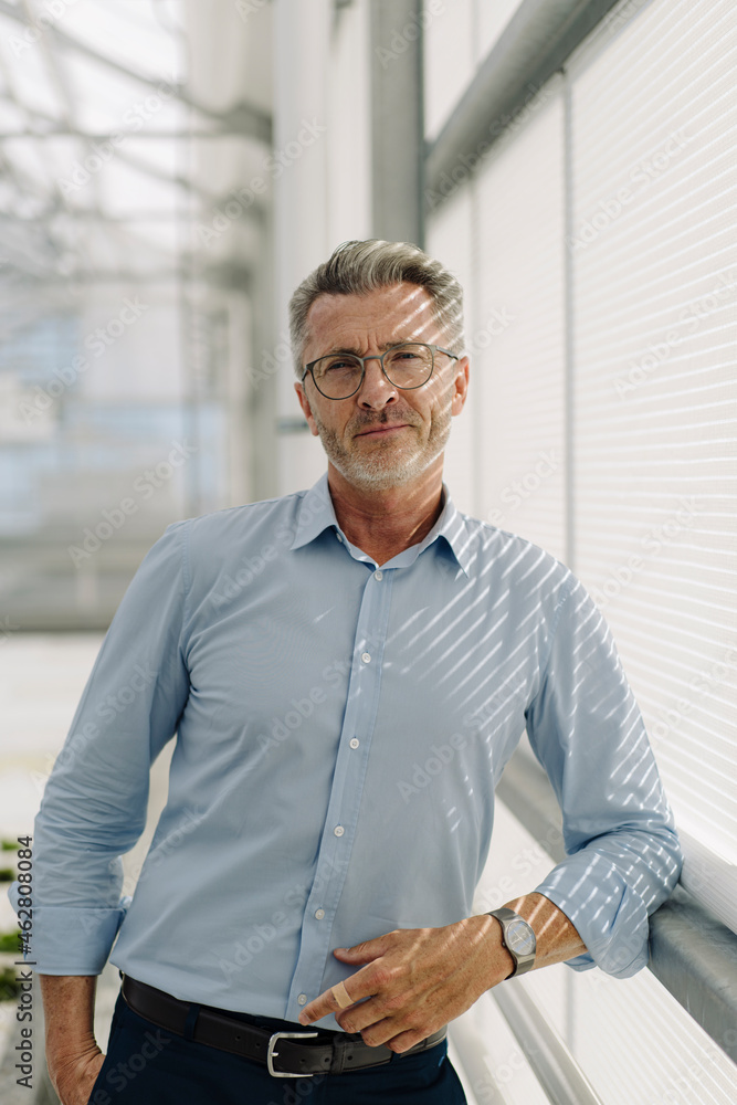 Handsome male professional standing by window in greenhouse Handsome male professional standing by window in greenhouse