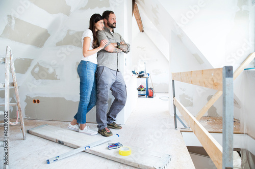 Couple in attic to be renovated looking out of window