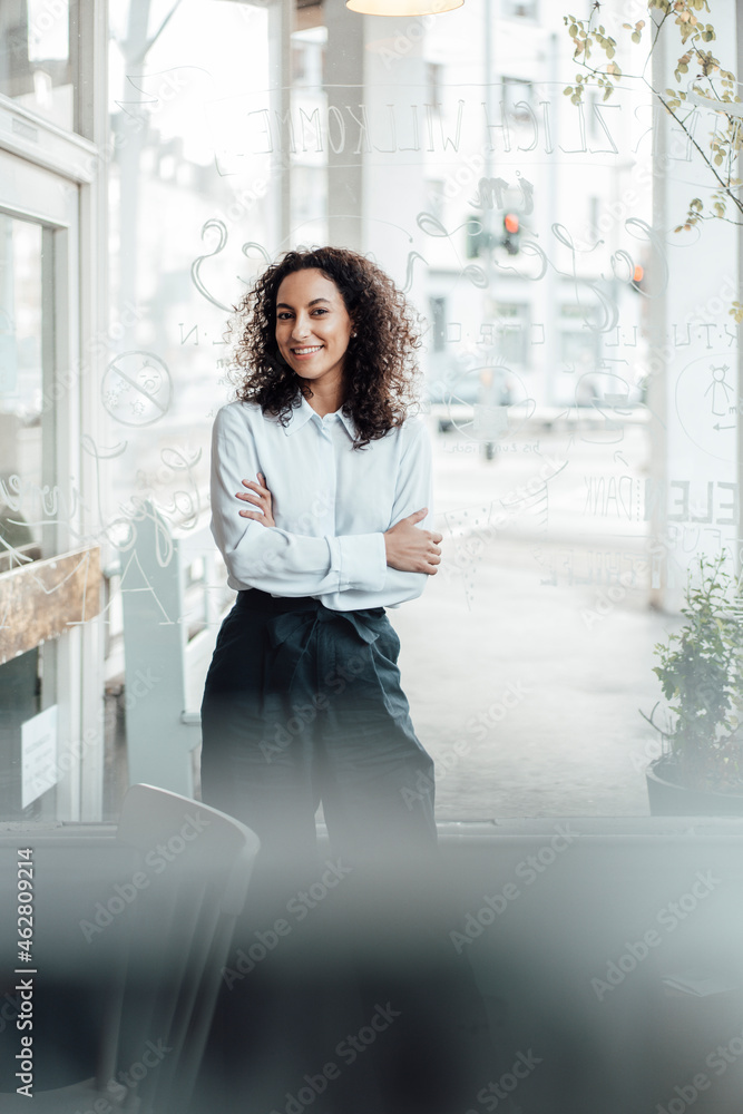 Smiling businesswoman standing with arms crossed at cafe Smiling businesswoman standing with arms crossed at cafe