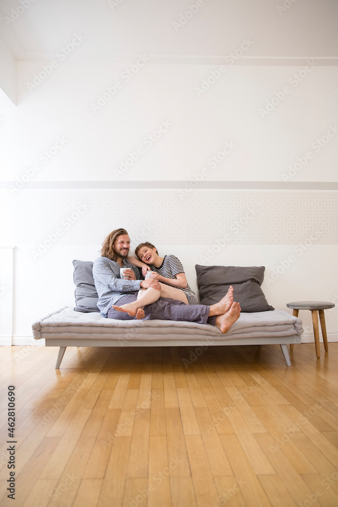 Happy young couple in pyjamas on bed couch at home Happy young couple in pyjamas on bed couch at home