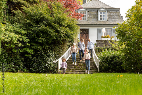 Extended family walking on stairs in garden of their home