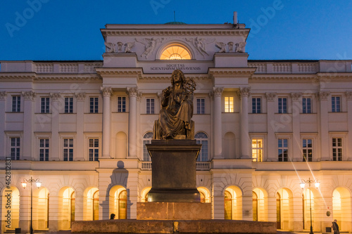 Illuminated presidential palace with monument of Nicolaus Copernicus in the foreground, Warsaw, Poland photo