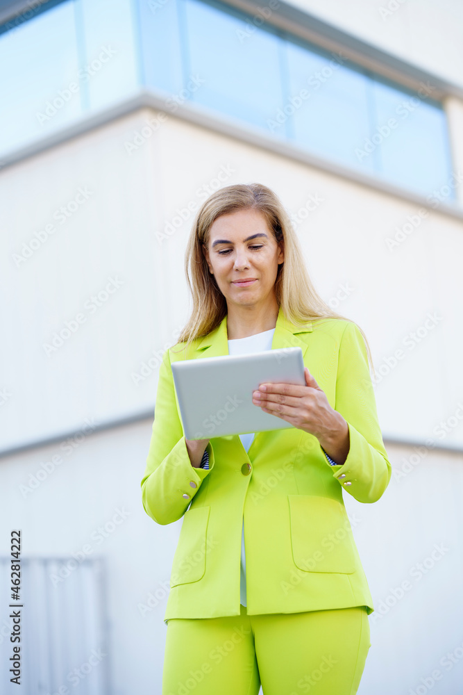 Businesswoman using digital tablet while standing against building Businesswoman using digital tablet while standing against building