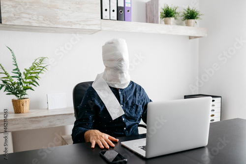 Man working at home with his head covered in toilet paper photo