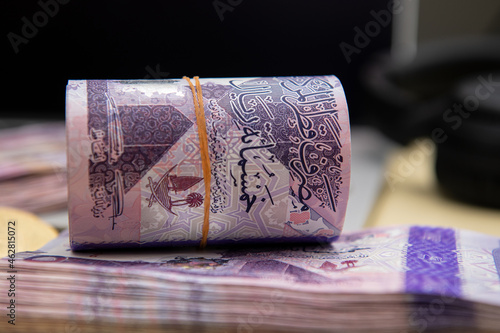 Bitcoin Cryptocurrency on Qatari 500 Riyal banknotes. Selective focus photo