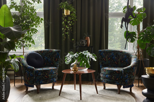 Fotografia Extraordinary living room interior composition with two designed armchairs, wooden coffee tabqle, a lot of plants and stylish personal accessories