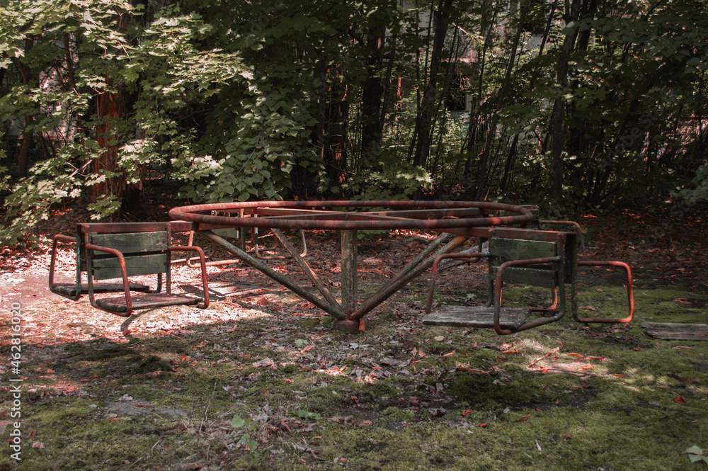 A radioactive abandoned  playground overgrown with trees in the city of Pripyat