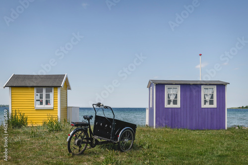 Denmark, Region of Southern Denmark, Aeroskobing, Old-fashioned tricycle standing in front of small coastal bathhouses photo