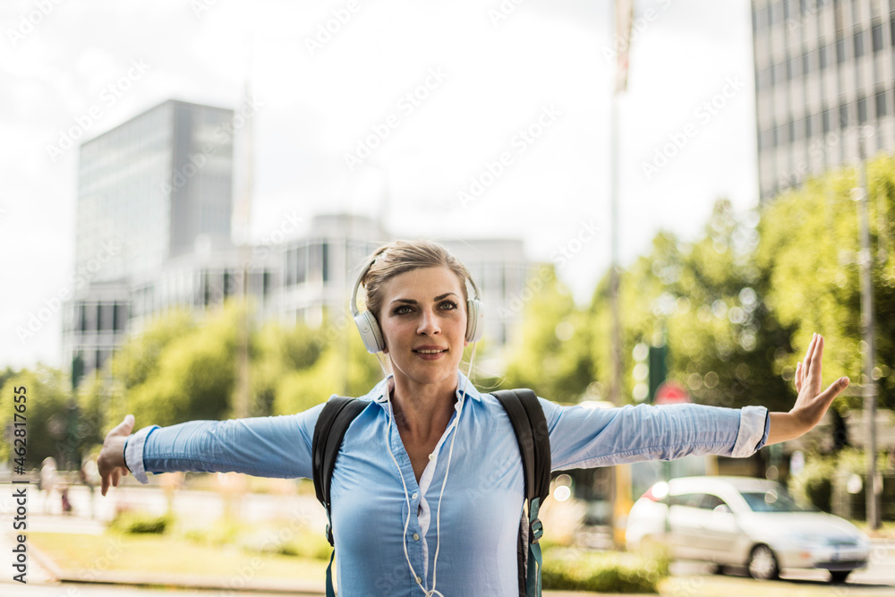 Smiling woman with backpack in the city wearing headphones Smiling woman with backpack in the city wearing headphones