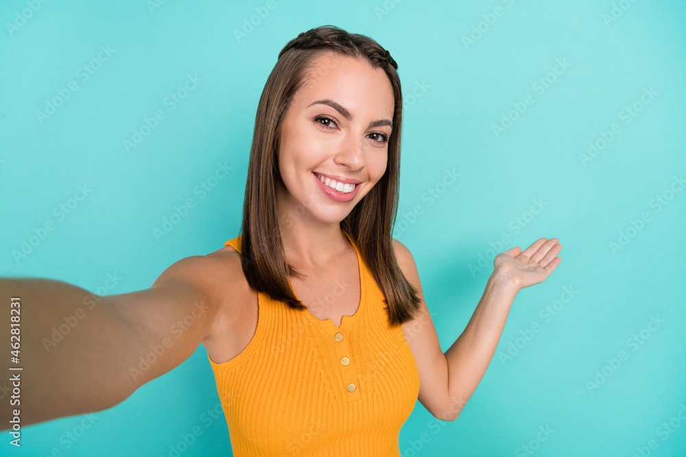 Photo of charming positive happy woman make selfie invite you hand empty space isolated on teal color background Photo of charming positive happy woman make selfie invite you hand empty space isolated on teal color background