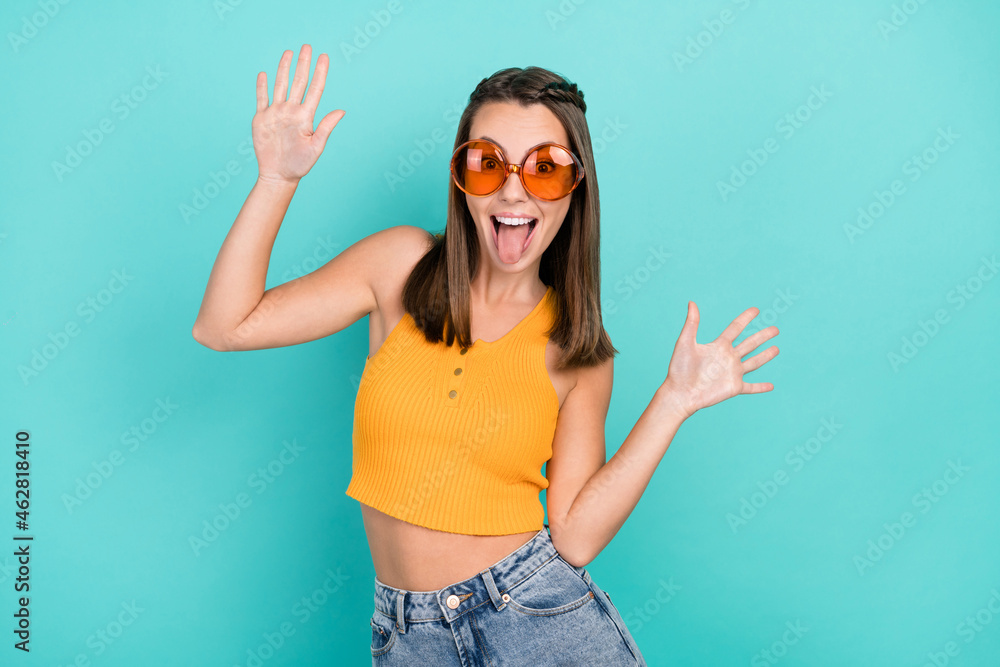 Photo of crazy positive funky happy woman raise hands wear sunglass funny face isolated on teal color background Photo of crazy positive funky happy woman raise hands wear sunglass funny face isolated on teal color background