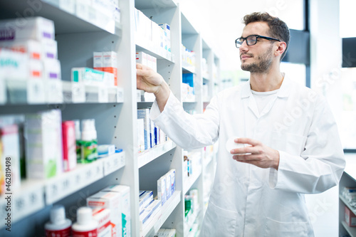 Pharmacist taking medicine from shelf in pharmacy