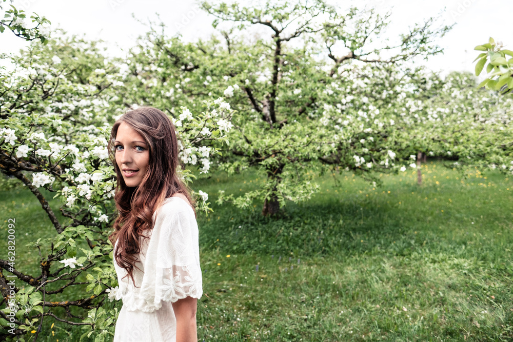 Portrait of smiling young woman in garden with blossoming apple trees Portrait of smiling young woman in garden with blossoming apple trees
