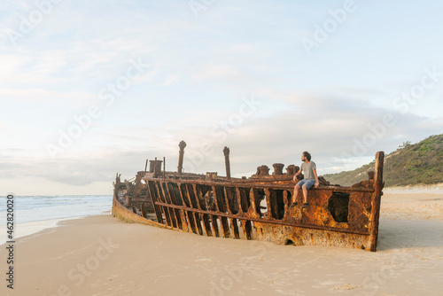 Man sitting on Maheno shipwreck at Fraser Island, Queensland, Australia photo