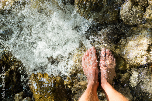 Man's feet standing on stone in a brook photo