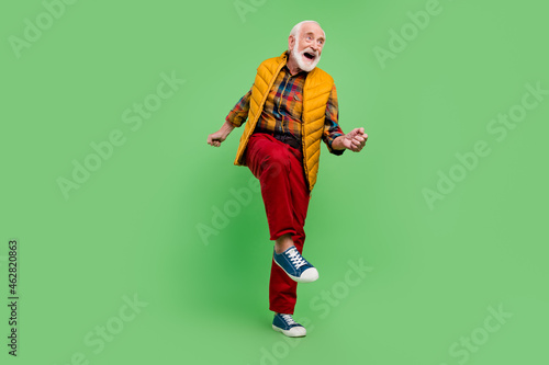 Photo of pretty funny mature man dressed yellow waistcoat smiling dancing isolated green color background