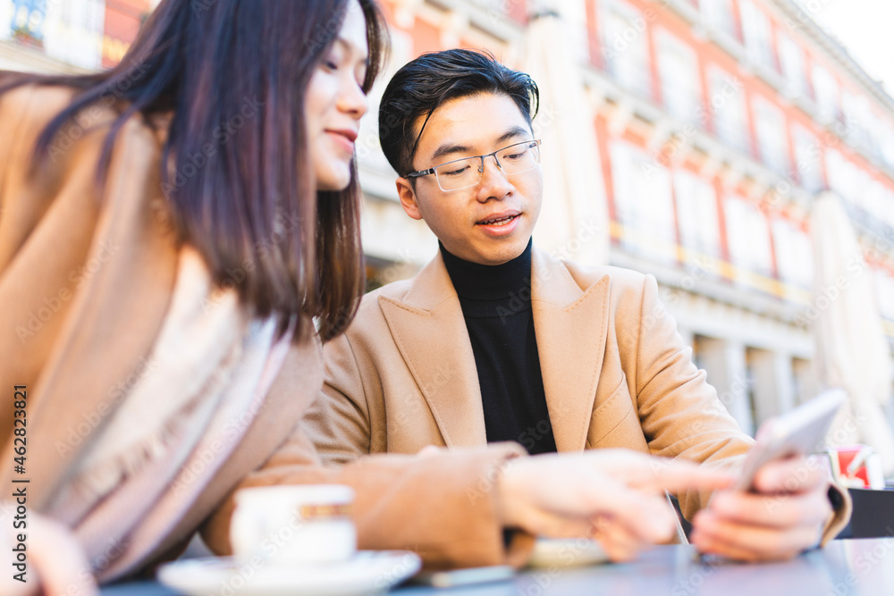 Spain, Madrid, young couple using cell phone in a cafe at Plaza Mayor Spain, Madrid, young couple using cell phone in a cafe at Plaza Mayor
