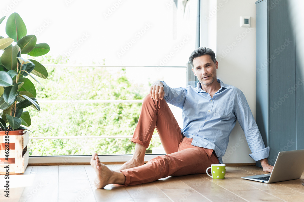 Mature man relaxing at home with a cup of coffee, using laptop Mature man relaxing at home with a cup of coffee, using laptop