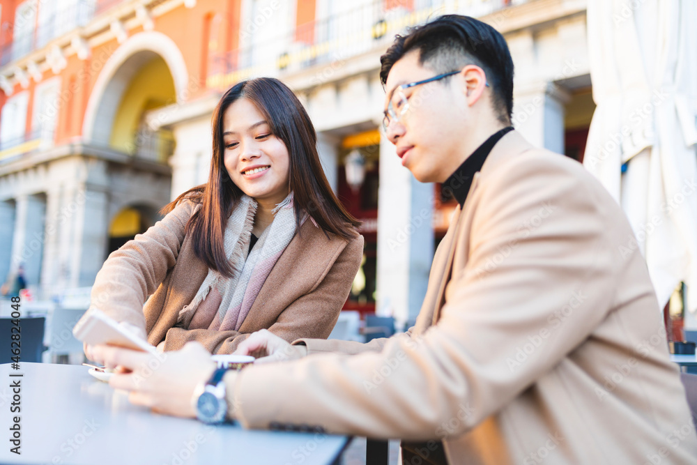 Spain, Madrid, young couple using cell phone in a cafe at Plaza Mayor Spain, Madrid, young couple using cell phone in a cafe at Plaza Mayor