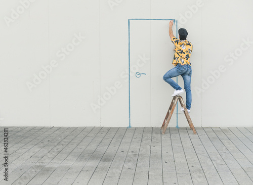 Digital composite of young man drawing a door at a wall