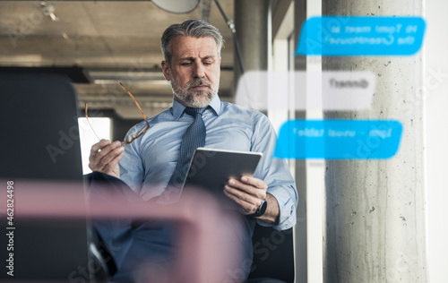 Mature businessman using tablet for messaging in the office photo