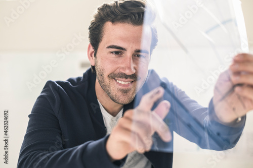 Young businessman in office holding foil of a blueprint photo