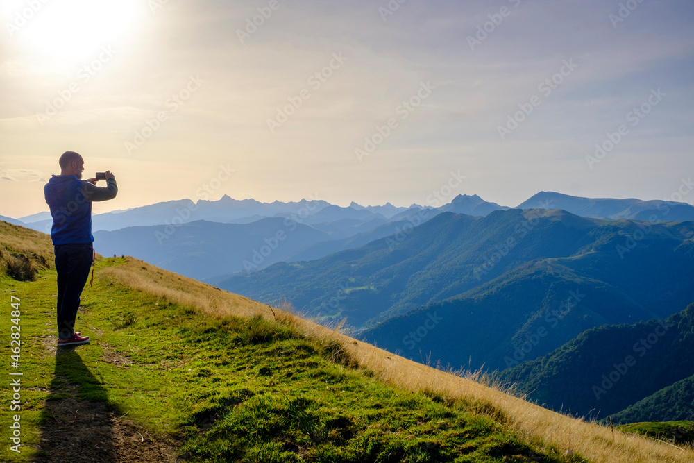 France, Pyrenees-Atlantiques, Larrau, Male hiker taking photos from Col dOrgambidesca at sunset France, Pyrenees-Atlantiques, Larrau, Male hiker taking photos from Col dOrgambidesca at sunset