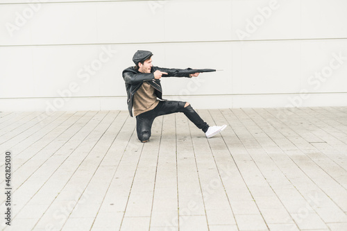 Young man pretending to shoot with closed umbrella photo