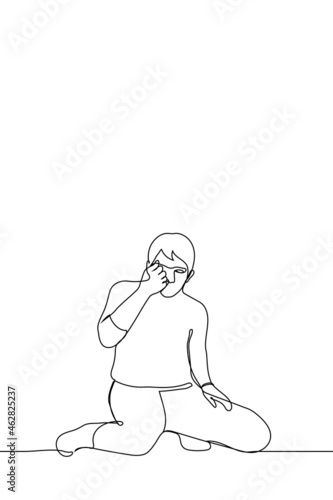 man sits on knees he looks at his tightly clenched fist - one line drawing. concept of catching insect with hand; find a jewel; consider something very small