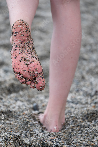 Woman foot covered with gravel while standing on beach photo