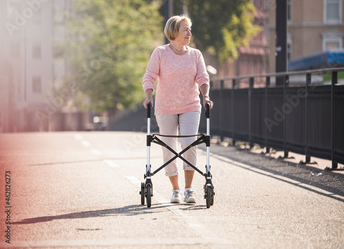 Senior woman with wheeled walker on footbridge