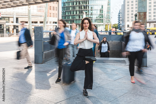 Young businesswoman practising yoga in the city at rush hour, Berlin, Germany