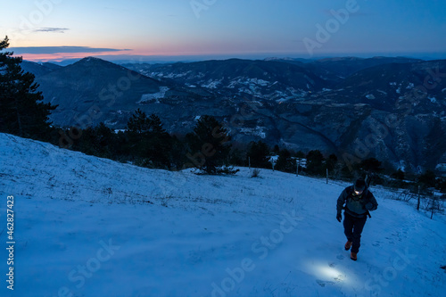 Italy, Province of Pesaro and Urbino, Male hiker ascending snowcapped ridge of Monte Acuto photo