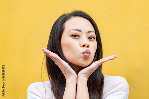 Portrait of woman against yellow background pouting mouth