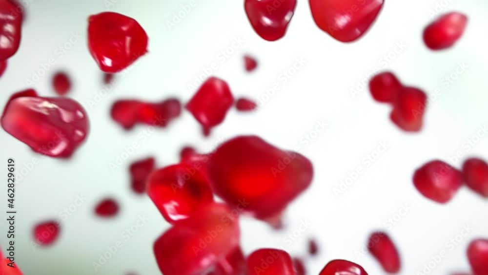 Super close-up of juicy grains of pomegranate falling on the white background Super close-up of juicy grains of pomegranate falling on the white background