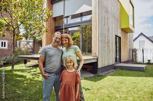 Smiling daughter standing with parents against tiny house in yard photo