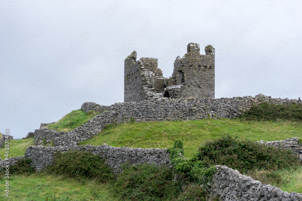 old castle ruin of a tower on a green grass hill on the Aran Islands